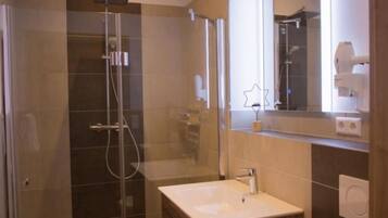 A modern bathroom with a glass-enclosed shower, a vanity with a sink, and a mirror.