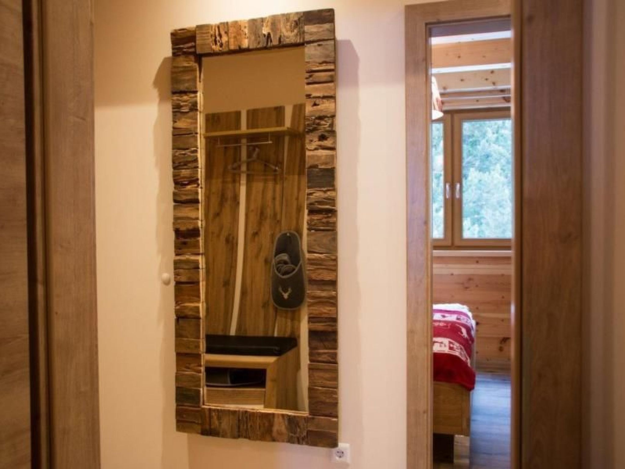 Una habitación con paneles de madera, un espejo y una cama con una colcha roja.