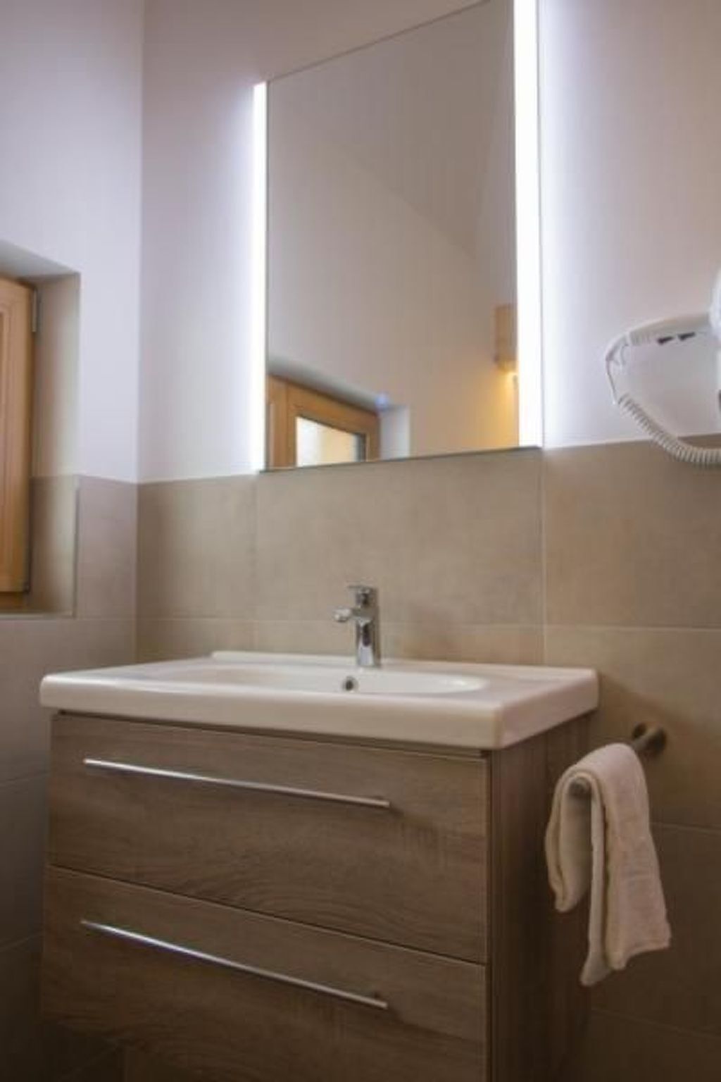 Un baño con lavabo, espejo y perchero para toallas.