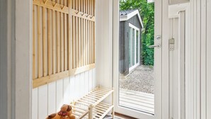 A wooden bench with a dog toy, a door leading to a covered outdoor area, and a white wall with vertical wooden slats. - "Maini" - 30km from the sea by Interhome (Toftlund)