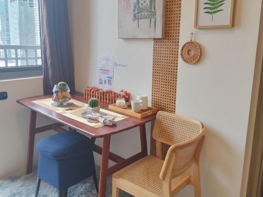 Ein Zimmer mit einem Holztisch, zwei Stühlen, einem mit Vorhängen versehenen Fenster, einem gerahmten Bild und einem Wanddekor.