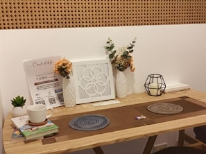Una mesa de madera con un cuadro enmarco, una planta pequeña en maceta, un candelabro y un jarrón decorativo.