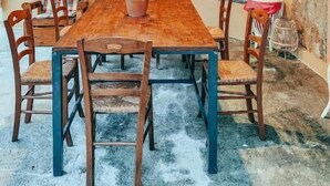 Una mesa de comedor de madera con sillas, una lámpara colgante, una ventana con diseño de cuadrícula y un reloj fijado a la pared.