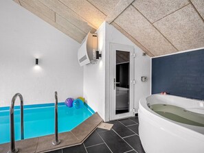 Ein modernes Badezimmer mit Badewanne, Duschbereich und Pool.