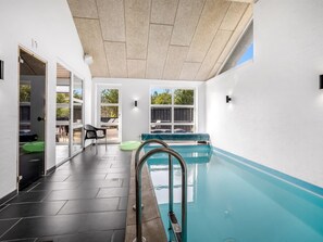 A swimming pool with a view of the outdoors, a door leading to a patio area, and a chair by the pool. - "Ozrenka" -  from the sea by Interhome (Hals)