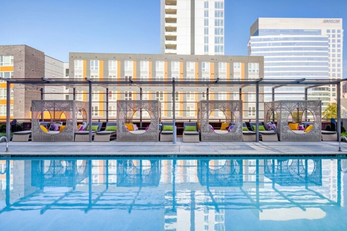 A poolside area with lounge chairs and a view of a multi-story building in the background.