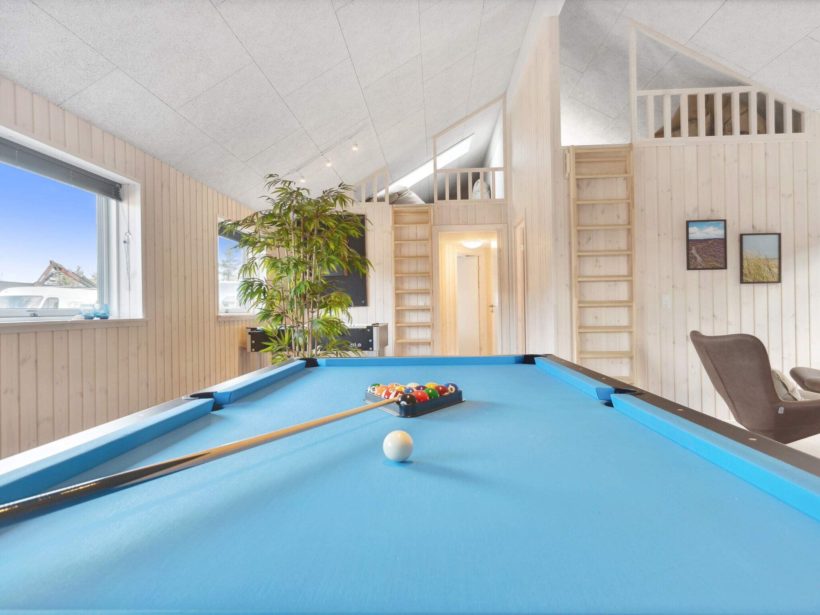 Et poolbord med blå filtdug, en hvid billardkugle og et sæt farverige kugler.