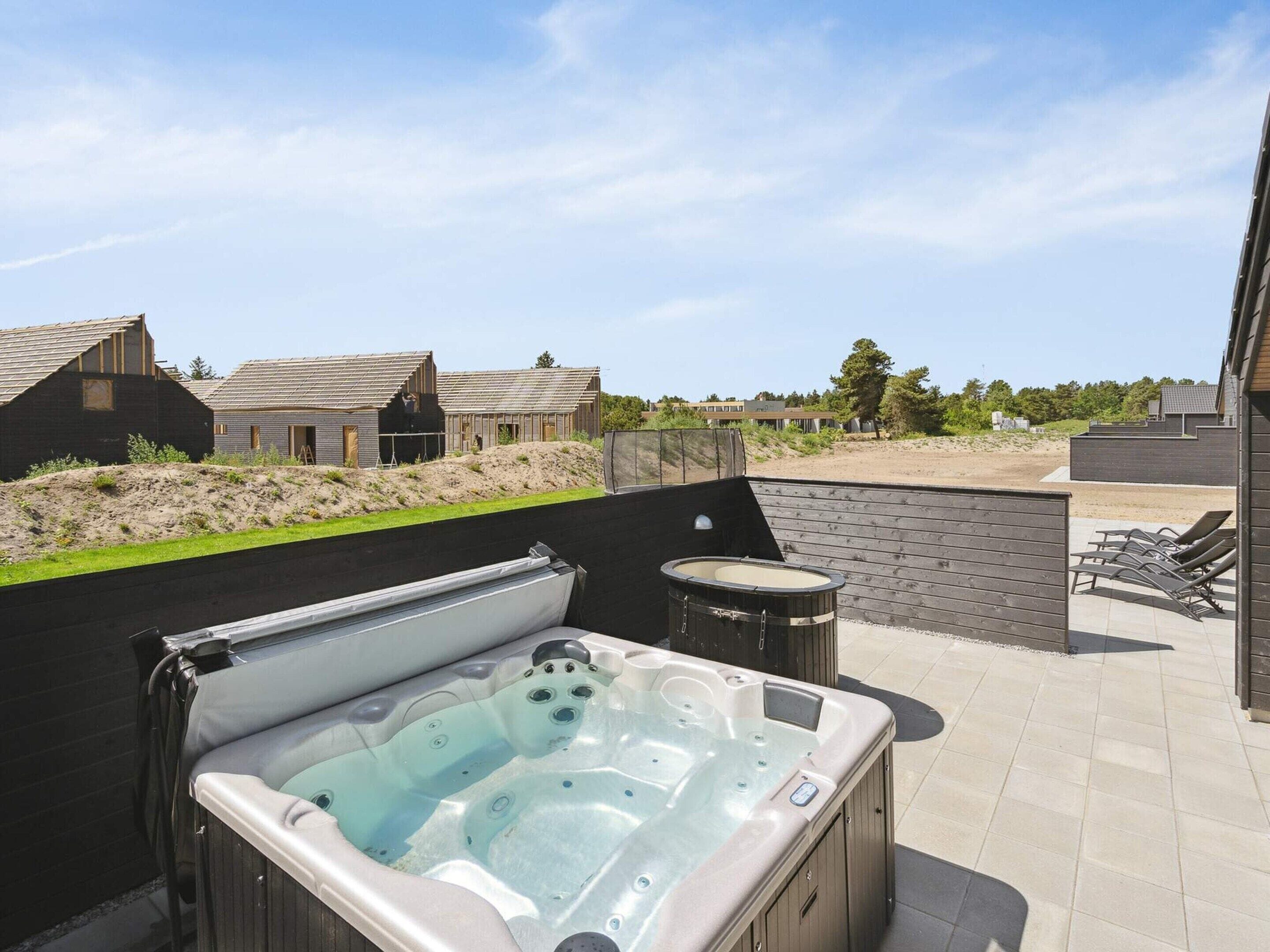 A hot tub with a view of a residential area and a sandy beach in the background.