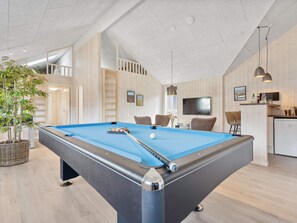A pool table in a room with a high ceiling, wooden walls, and a kitchen area. - 5 Star Holiday Home in Romo (Rømø)