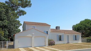 Ein zweistöckiges Haus mit Garage, kleiner Veranda und umzäuntem Garten.