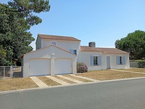 Ein zweistöckiges Haus mit Garage, kleiner Veranda und umzäuntem Garten.