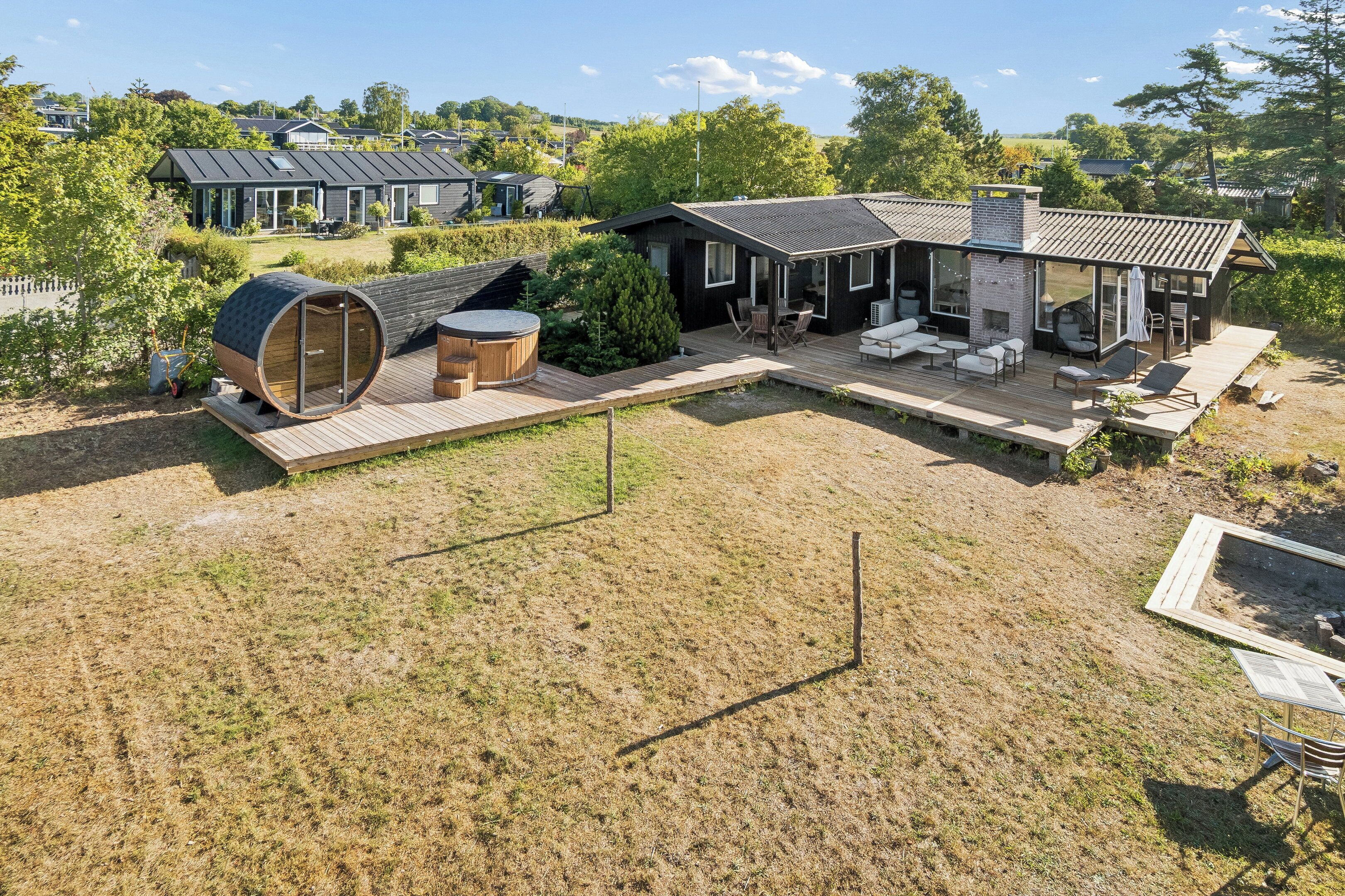 A modern house with a deck, outdoor seating, and a sauna.