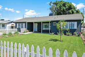 A single-story house with a front porch, a small lawn, and a white picket fence. - Games, Fenced Yard & Covered Trailer Parking (Phoenix)
