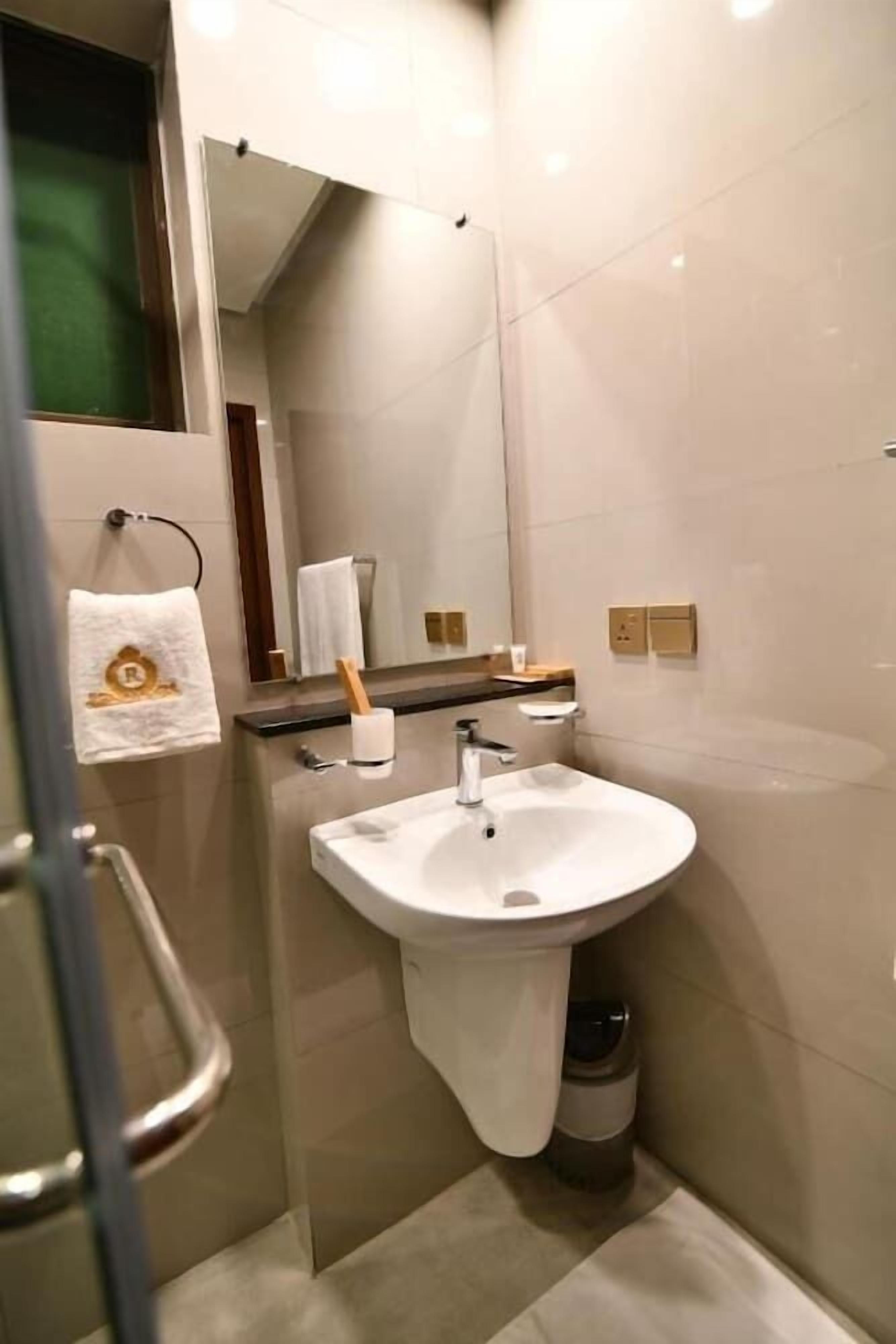 A modern bathroom with a white sink, mirror, and towel rack.