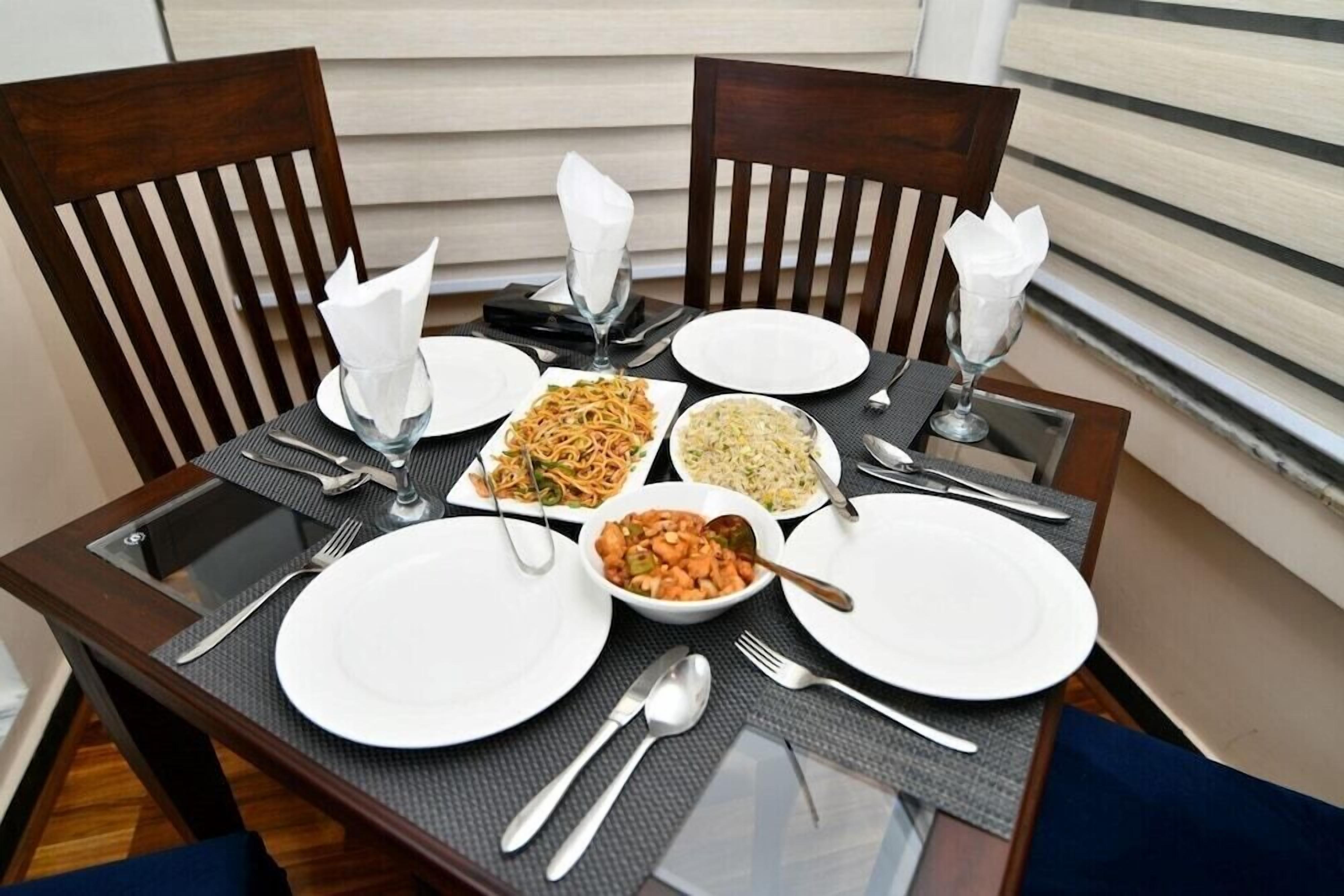 A dining table set with plates, cutlery, and bowls of food.