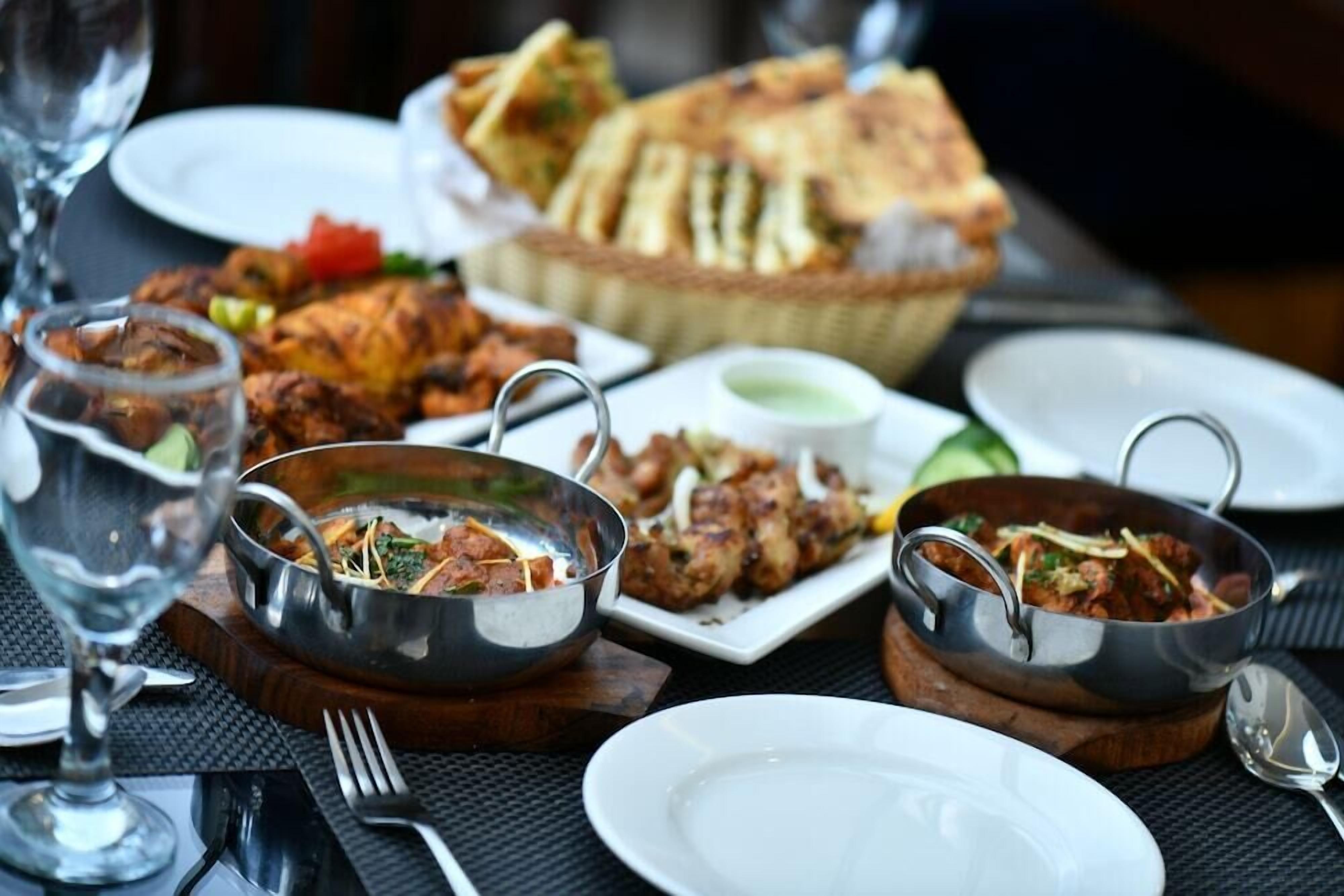 A table set with various dishes, including a bowl of soup, a plate of meat, and a basket of bread.