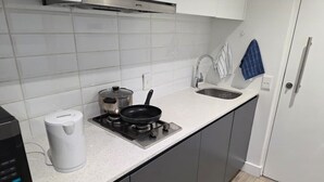 Ett modernt kök med en gasspis, en vattenkokare och en kaffebryggare.