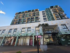 Een meerlaags gebouw met een modern ontwerp, met een opvallend 'ALBERT' bord op de begane grond.