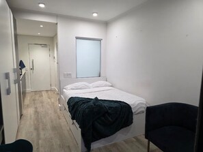 A small, modern bedroom with a bed, a chair, a window, and a door. - Fantastic 1-bedroom studio in vibrant Cape Town near top spots (Cape Town)