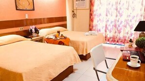 A hotel room with two beds, a small table with a cup, a chair, and a window with curtains.