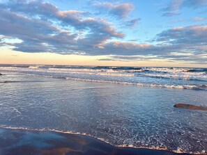 A beach with waves and a clear sky.