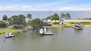 Um imóvel à beira do lago com um píer, uma casa pequena e um barco.