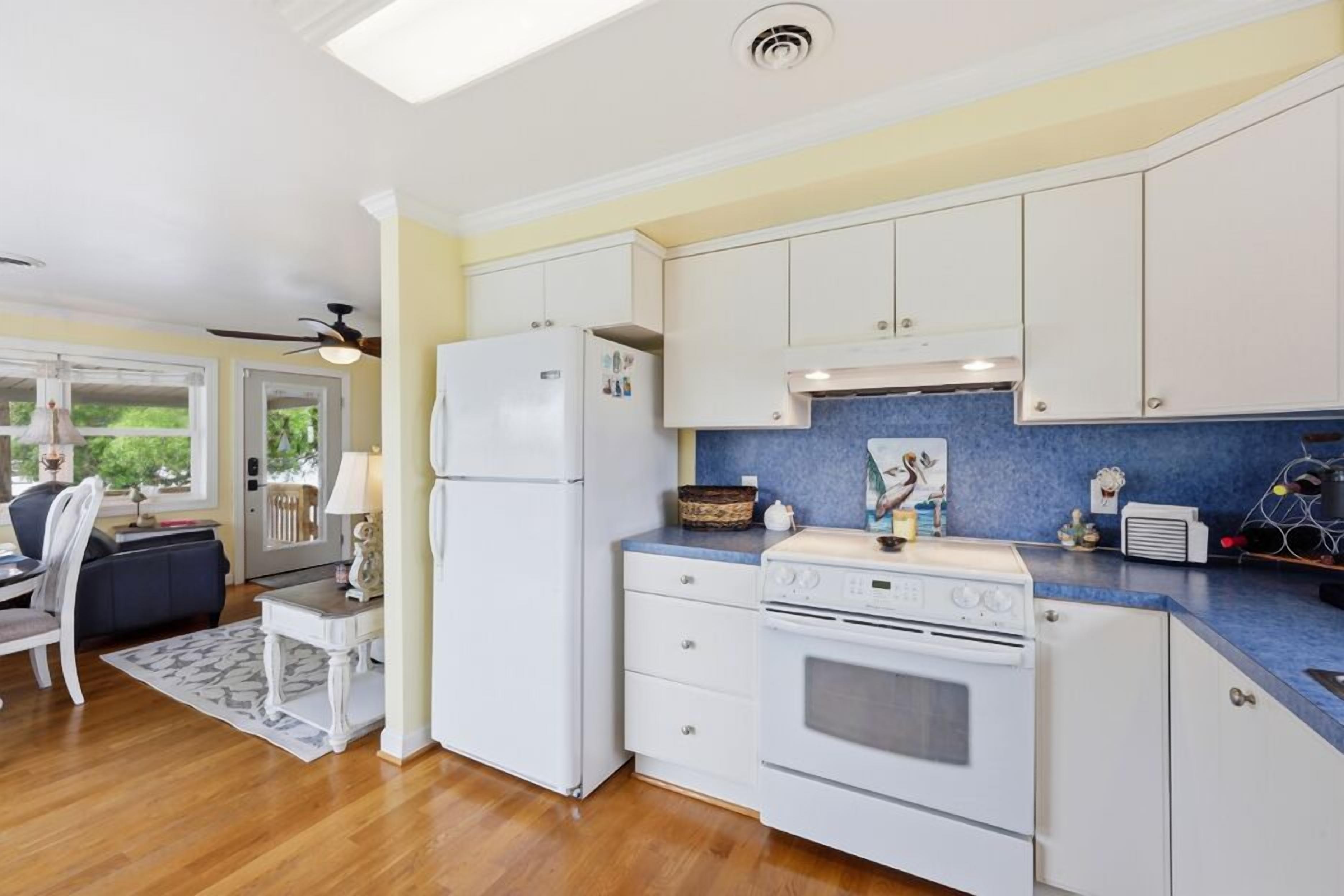 A kitchen with white cabinets, a refrigerator, an oven, and a blue countertop.