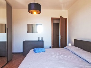 A bedroom with a bed, a bedside table, a mirror, a wardrobe, and a door. - Sondolo by Interhome (Pescia)