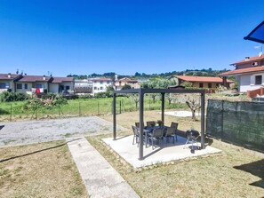 A residential area with a patio area featuring a table and chairs, a barbecue grill, and a pergola structure. - Sondolo by Interhome (Pescia)