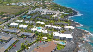 An aerial view of a coastal hotel with multiple buildings, a parking lot, and a swimming pool. - Little Kona Getaway with AC & heated oceanfront pool 1 BD 1 BA with sleeper sofa (Kailua Kona)