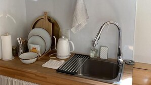 Una cocina moderna con un lavamanos de acero inoxidable, una cafetera y un colgador con tazas y vasos.