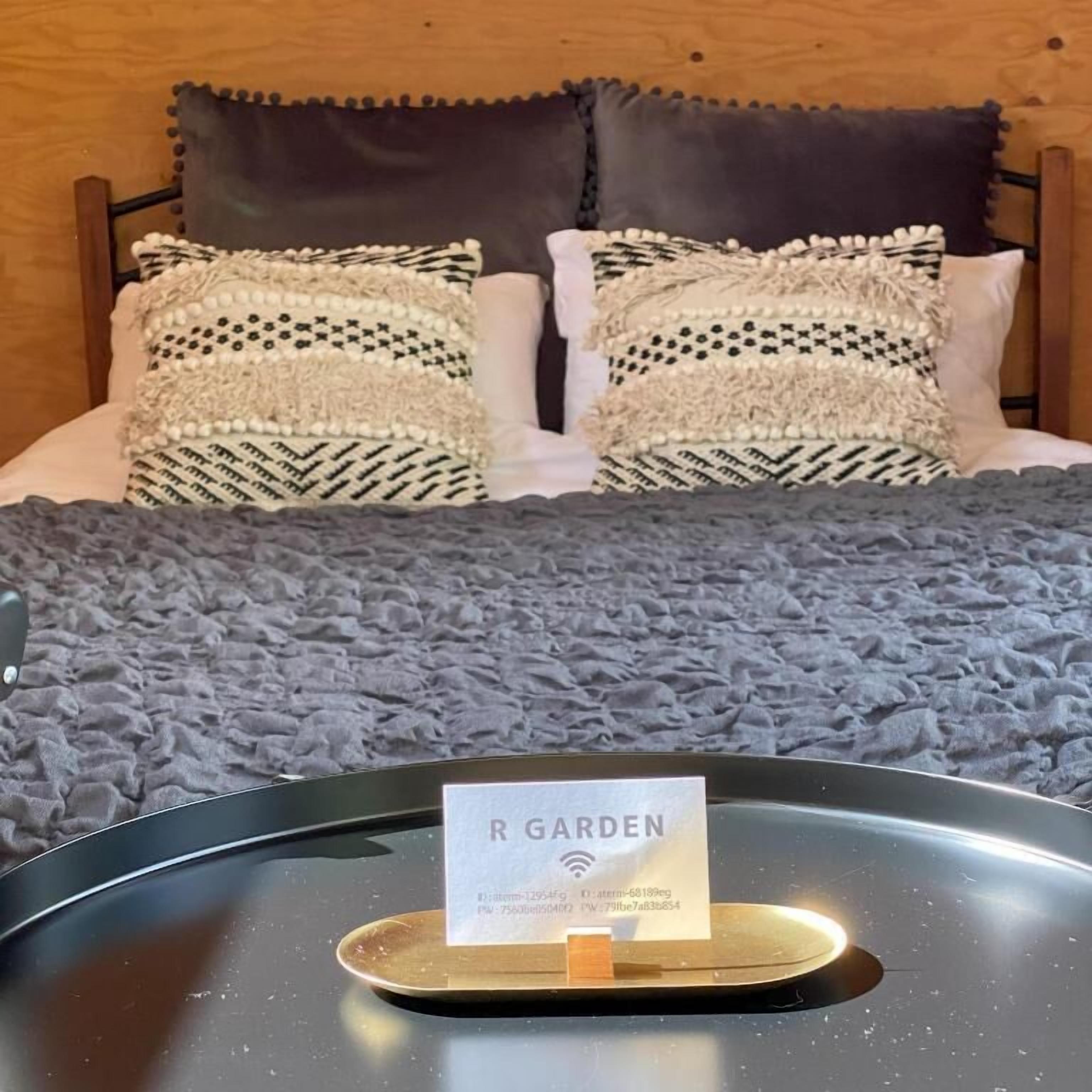 Uma cama com almofadas estampadas, um cobertor cinzento e uma placa indicando vista para o jardim.