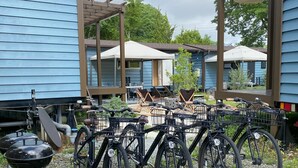 A courtyard with bicycles parked, a barbecue grill, and outdoor seating under a pergola. - R GARDEN (Yamanakako)