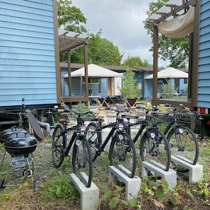 Un patio con bicicletas estacionadas, una parrilla y mobiliario exterior bajo una pérgola.