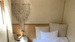 A bedroom with a bed, a bedside table with a lamp, a macrame wall hanging, and a wooden headboard. - R GARDEN (Yamanakako)