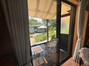 Habitación con puerta de vidrio corredera que da a un patio exterior con mesa, sillas y un pequeño jardín.