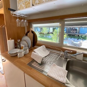 Una cocina con un lavabo, un escurreplatos y una ventana con vistas al exterior.
