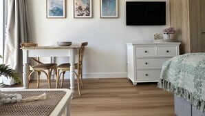 A room with a dining table, chairs, a TV mounted on the wall, and a cabinet. - Beachfront Studio, Views, Best Location (Dee Why)