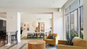 Ein modernes Interieur mit einem runden Holztisch, gelben Armstühlen und einem Essbereich mit Stühlen und einem weißen Tisch.