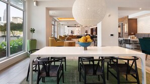 A modern dining area with a large table, chairs, and a central decorative bowl. - Cozy Carolina - Free Parking, Gym, Pool (Charlotte)