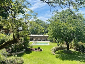 A backyard with a swimming pool, a wooden deck, and a stone wall. - Les Clés du Boudoir: Charm and Elegance Near Hautefort & Montignac. (Saint Rabier)