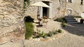 A stone building with a gravel courtyard, outdoor seating, and a staircase leading to an upper level. - Les Clés du Boudoir: Charm and Elegance Near Hautefort & Montignac. (Saint Rabier)