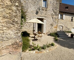 A stone building with a gravel courtyard, outdoor seating, and a staircase leading to an upper level. - Les Clés du Boudoir: Charm and Elegance Near Hautefort & Montignac. (Saint Rabier)