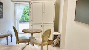 A bedroom with a bed, a chair, a small round table, and a wardrobe. - Les Clés du Boudoir: Charm and Elegance Near Hautefort & Montignac. (Saint Rabier)