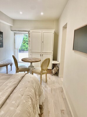 A bedroom with a bed, a chair, a small round table, and a wardrobe. - Les Clés du Boudoir: Charm and Elegance Near Hautefort & Montignac. (Saint Rabier)
