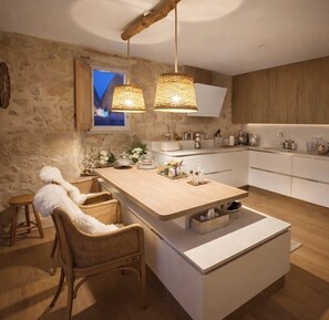 A modern kitchen with a central island, wooden chairs, and hanging pendant lights. - Les Clés du Boudoir: Charm and Elegance Near Hautefort & Montignac. (Saint Rabier)