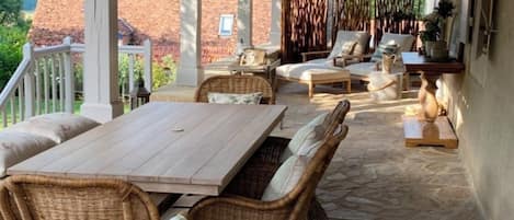 A covered patio area with a stone floor, wicker furniture, and a view of a brick building.