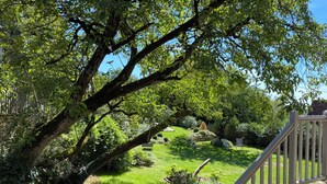 A garden with a stone wall, a wooden fence, and a grassy area with trees. - Les Clés du Boudoir: Charm and Elegance Near Hautefort & Montignac. (Saint Rabier)