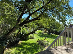 A garden with a stone wall, a wooden fence, and a grassy area with trees. - Les Clés du Boudoir: Charm and Elegance Near Hautefort & Montignac. (Saint Rabier)