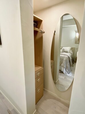 A bedroom with a wooden wardrobe, a mirror, and a bed with a white bedspread. - Les Clés du Boudoir: Charm and Elegance Near Hautefort & Montignac. (Saint Rabier)